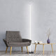 Moderne Sting LED-Stehleuchte in Schwarz neben einem eleganten Sessel und Holztisch im minimalistischen Raum.
