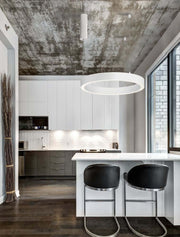 Moderne Küche mit Sting LED Pendelleuchte Ø 60cm 3000K über einer weißen Insel und stylischen schwarzen Barhockern.