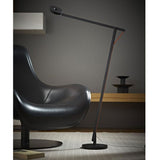 Moderne Rotaliana String LED-Stehleuchte in Schwarz neben einem eleganten Sessel im minimalistischen Wohnraum.