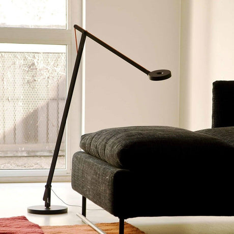 Rotaliana String LED floor lamp with Push Dimm To Warm White next to a sofa in a modern interior.
