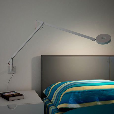 Rotaliana String LED wall light with dimmer White above a bed with colorful bedding and bedside table.