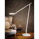 Rotaliana String XL LED-Stehleuchte mit Dimmer Weiß neben einem Sofatisch und einem Sessel.