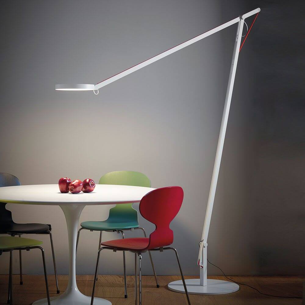 Rotaliana String XL LED-Stehleuchte mit Dimmer Weiß über einem modernen Tisch mit bunten Stühlen.