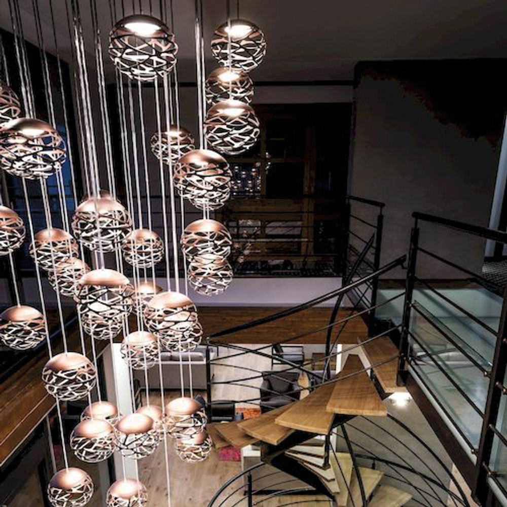 Lodes Kelly Cluster Sphere LED Pendellampe in stilvollem Innenraum mit spiralförmiger Treppe.