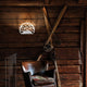 Lodes Kelly Wandlampe an einer Wand in einem rustikalen Interieur mit Holzverkleidung.