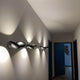 Lodes Nautilus LED Wandlampe 2300 Lumen an einer Wand im Flur, effizient und modern beleuchtend.