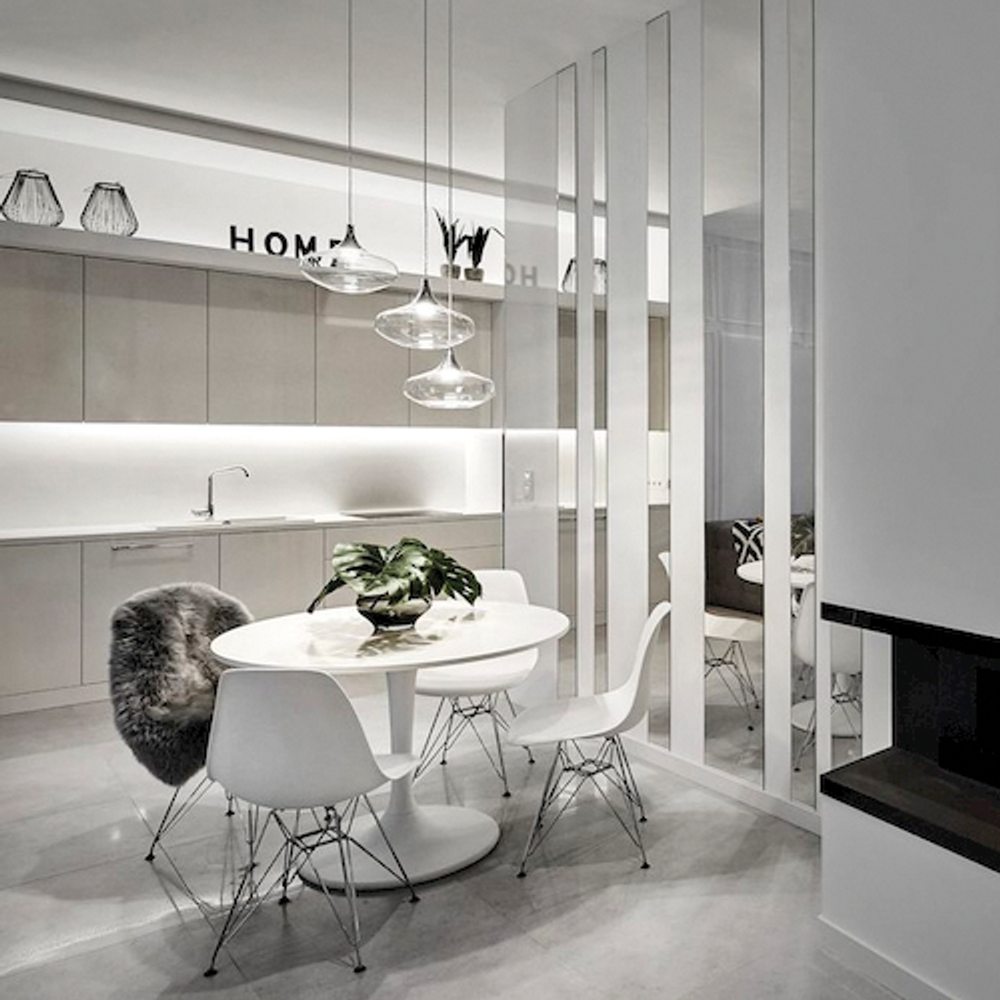 Moderne Küche mit Tisch, Stühlen, Pflanzen und eleganter Pendelleuchte im Retro-Stil.