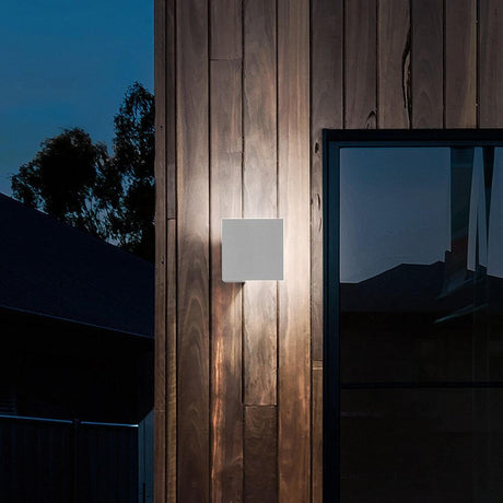 Lodes Puzzle Outdoor Single Square LED wall light on a wooden facade outdoors at dusk.