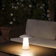 Task Outdoor LED-Tischlampe USB IP54 Weiß auf einem Tisch in einem Garten. Warmes Licht und pilzförmiges Design.