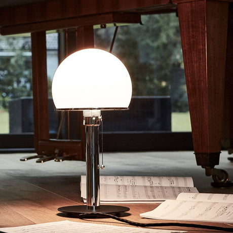 Tecnolumen Wilhelm Wagenfeld Bauhaus-bordlampe WA23SW svart på et bord med noter.