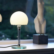 Moderne Tischlampe mit opalweißem Schirm und Glasfuß auf der Fensterbank