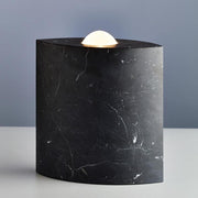 Tecnolumen floor lamp Egyptian Eye marble black-polished on a table with elegant lighting.