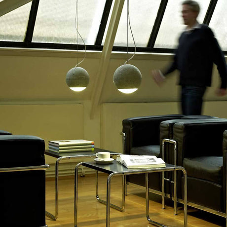Tecnolumen betongpendellampe Trabant 1 dreibar med linse i moderne stue-design.