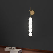 Terzani Abacus LED Væglampe med 5 kugler på en grå væg med elegante hvide kugler.