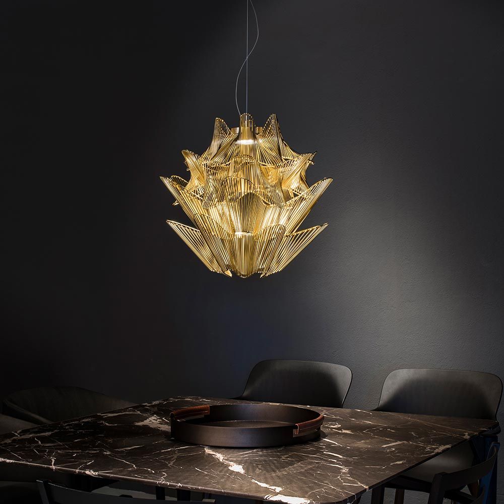 Terzani Moiré Kronleuchter Ø 65cm mit goldenem Design über einem Tisch, elegant im Raum beleuchtet.
