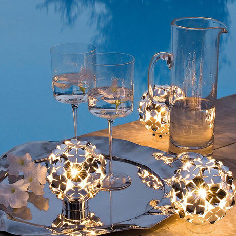 Elegant Terzani Orten'zia designer table lamp with glasses and a carafe on a silver tray at night.