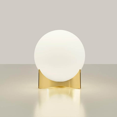 Terzani Oscar design table lamp with a round glass globe and a gold base on an elegant table.