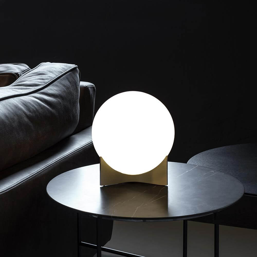 Terzani Oscar Design-Tischlampe auf einem Tisch mit schwarzem Hintergrund und Sofakissen.