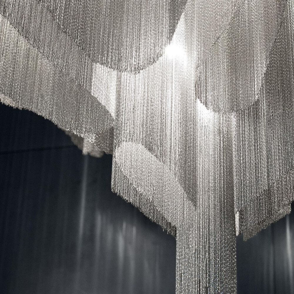 Nahaufnahme der Terzani Stream Design-Deckenlampe mit metallischen Ketten, die ein eindrucksvolles Licht erzeugen.