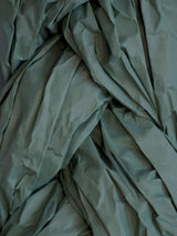 Struktur eines gefalteten, teils zerknitterten grünen Stoffes, ideal für textile Design-Projekte.