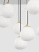 The Egg Pendelleuchte 12-flammig Ø 75cm Gold, Weiß, Schwarz mit opalen Glasschirmen in einem modernen Raum.
