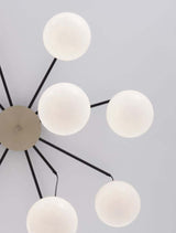 Moderne Pendelleuchte mit sechs opalen Glasschirmen in Gold, Schwarz und Weiß.