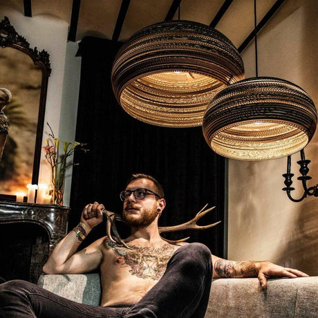 Suspension Dandy en carton ovale dans un salon moderne avec un homme et un intérieur élégant.