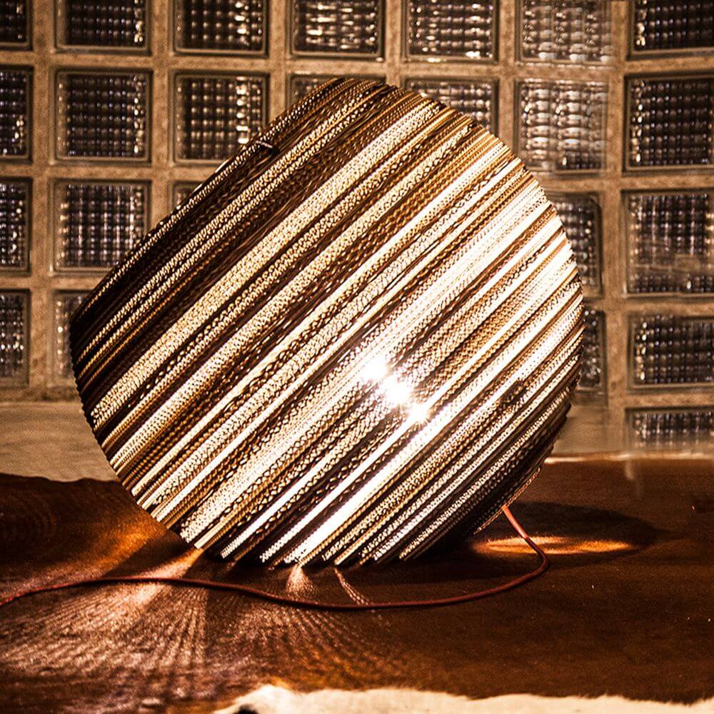 Globe Bodenleuchte aus Pappe auf einem Tisch mit warmem Licht und einzigartigem Design.