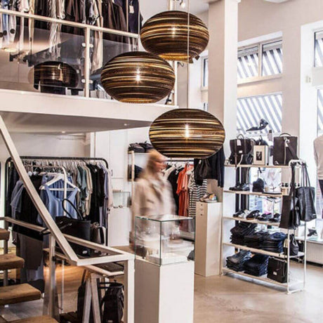 Suspension Lazy en papier ovale moderne dans une boutique de vêtements élégante avec un aménagement raffiné.