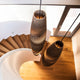 Zwei ovalen Pendelleuchten aus Pappe hängen über einer Holztreppe in modernem Innenraum.