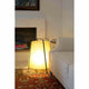 Tischlampe AKANE Schwarz, Beige neben einem Sofa mit Kamin, warme Beleuchtung.