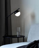 Tischlampe Contina auf einem Beistelltisch neben einem grauen Sofa mit Glaskaraffe.
