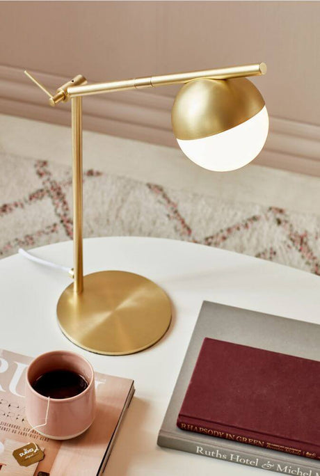 Tischlampe Contina mit kugelförmiger Glaskuppel und elegantem, goldfarbenem Metallgestell.