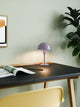 Tischlampe Ellen Mini auf einem Schreibtisch mit grünem Hintergrund, ideal für minimalistisches skandinavisches Design.