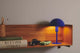 Tischlampe Ellen Mini auf einem Regal, beleuchtet mit skandinavischem Design, ideal für kleine Räume.