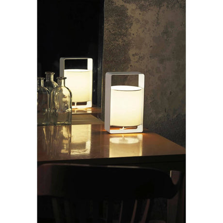 Lampe de table LULA avec abat-jour blanc sur une table, reflétée dans un miroir, lumière chaleureuse