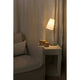 Tischlampe LUPE Chrom, Beige leuchtet neben einem Sofa und dekorativen Körben auf einem Tisch.