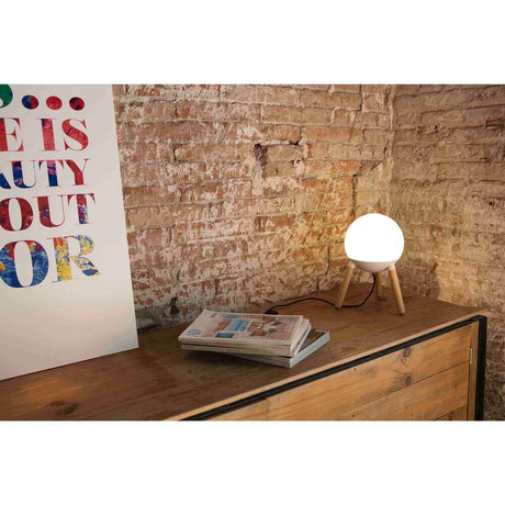 Lampe de table MINE sans diffuseur blanche sur un buffet en bois avec des magazines et une œuvre d’art en arrière-plan.