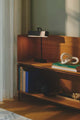 Tischlampe Merlin auf einem Holzregal, umgeben von Büchern und dekorativen Elementen.