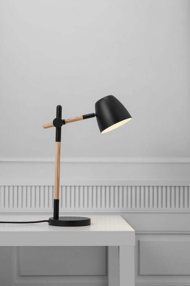 Tischlampe Theo in modernem Design mit Holz- und Metallkombination auf einem Tisch.