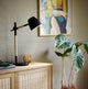 Tischlampe Theo auf einem Sideboard, kombiniert Holz und Metall für modernes Design.