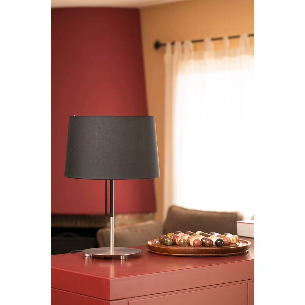 Tischlampe VOLTA Nickel-Matt, Schwarz auf einem Tisch mit dekorativem Tablett im Hintergrund.