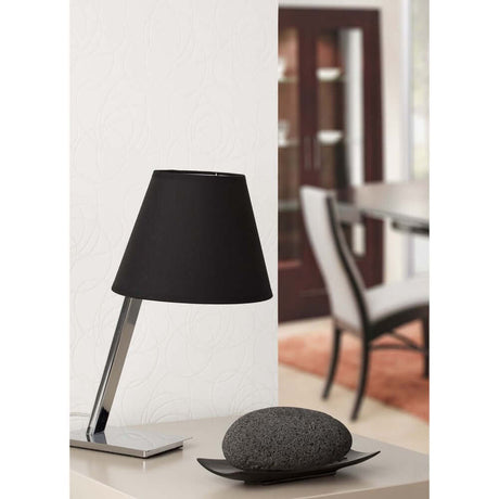 Tischleuchte MOMA Chrom, Schwarz auf einem Tisch neben einem dekorativen Stein.