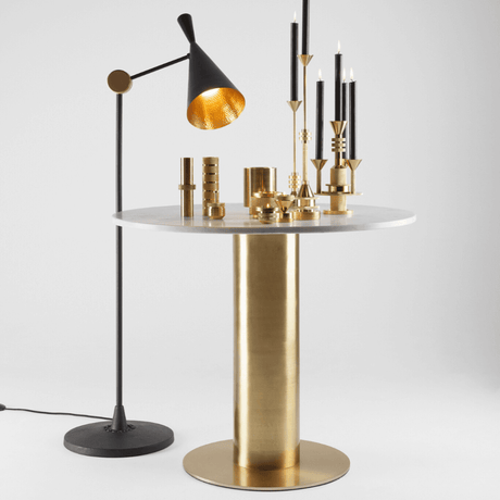 Tom Dixon Beat Stehleuchte verstellbar neben goldfarbenem Tisch und Dekoration.