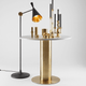 Tom Dixon Beat Stehleuchte verstellbar neben goldfarbenem Tisch und Dekoration.