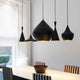 Tom Dixon Beat Stout Pendelleuchte aus Messing in Schwarz über dem Esstisch, elegant und modern.