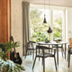 Tom Dixon Beat Tall LED Hängelampe Ø 19cm über einem Esszimmertisch in modernem Interieur, umgeben von Pflanzen.