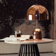 Tom Dixon Bell Tischleuchte mit Drehdimmer auf einem Tisch, polierte Oberfläche reflektiert die Umgebung.