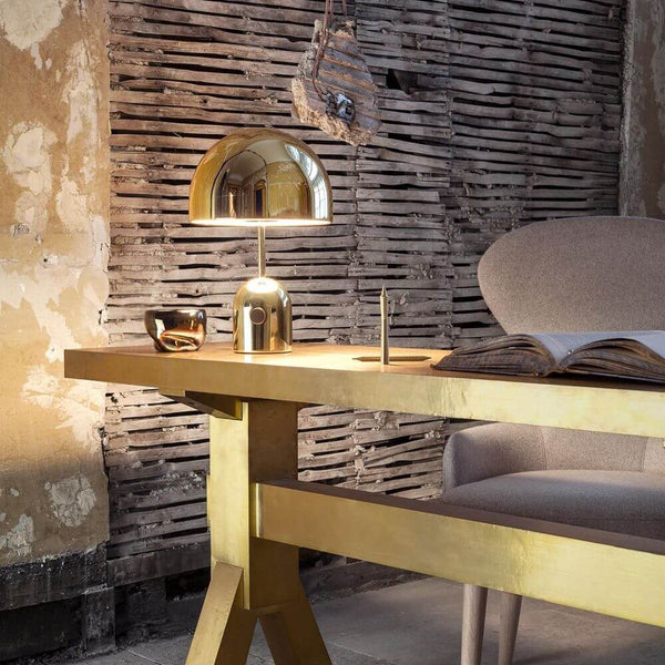 Tom Dixon Bell Tischleuchte mit Drehdimmer auf einem goldenen Tisch in modernem Interieur.