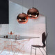 Tom Dixon Copper Pendelleuchte, hochreflektierende Oberfläche, Design für modernes Wohnen, in einem stilvollen Essbereich.